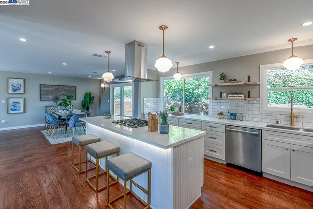 a kitchen with stainless steel appliances a sink a large window and wooden floor
