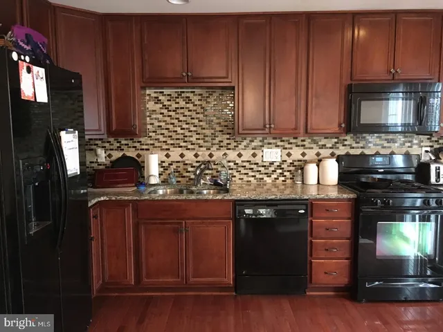 a kitchen with stainless steel appliances granite countertop wooden cabinets and a stove top oven