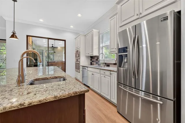 a kitchen with stainless steel appliances granite countertop a sink a oven and a wooden floors