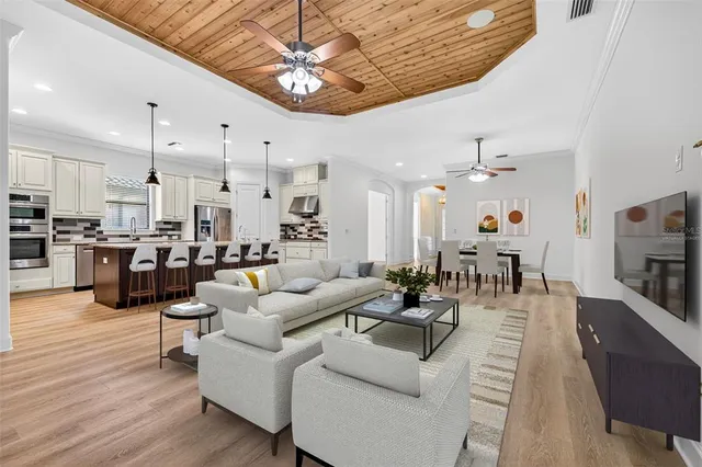a living room with furniture kitchen view and a wooden floor