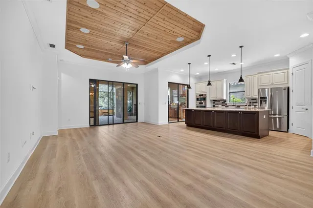 an empty room with wooden floor and fan