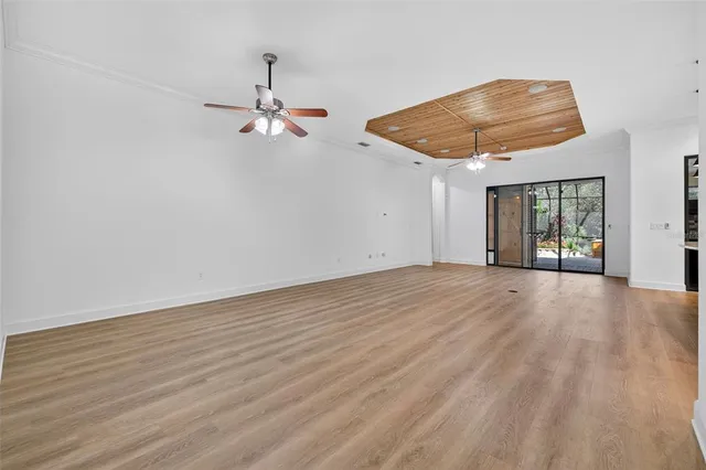 en empty room with wooden floor ceiling fan and window