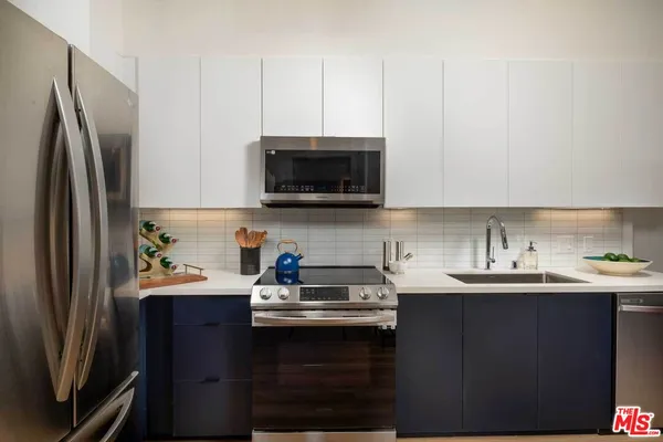 a kitchen with stainless steel appliances a sink a stove a refrigerator a sink a stove and cabinets