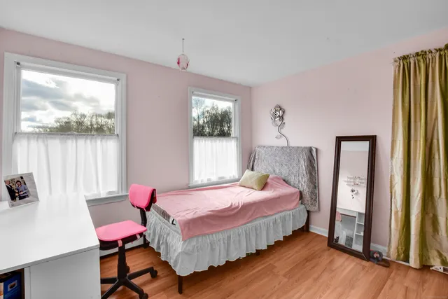 a bedroom with a bed a large window and wooden floor