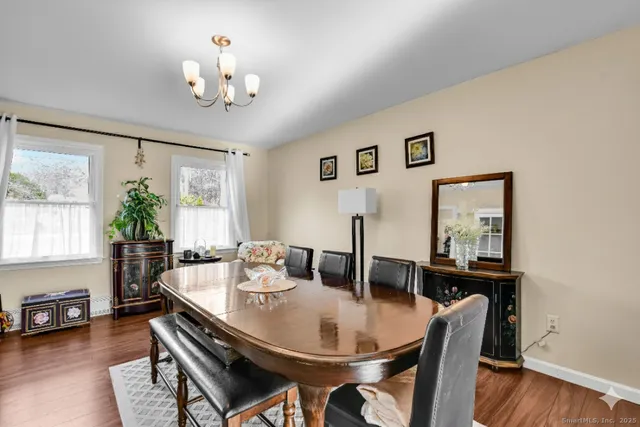 a dining room with wooden floor a chandelier a wooden table and chairs