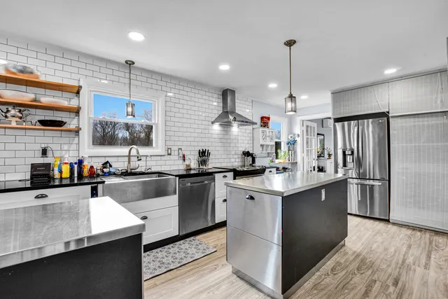 a kitchen with stainless steel appliances kitchen island granite countertop a sink stove and refrigerator