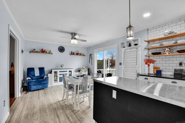 a kitchen with stainless steel appliances kitchen island granite countertop a sink dishwasher a stove a dining table and chairs with wooden floor