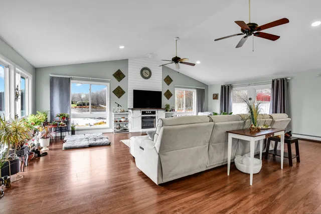 a living room with furniture kitchen view and a wooden floor