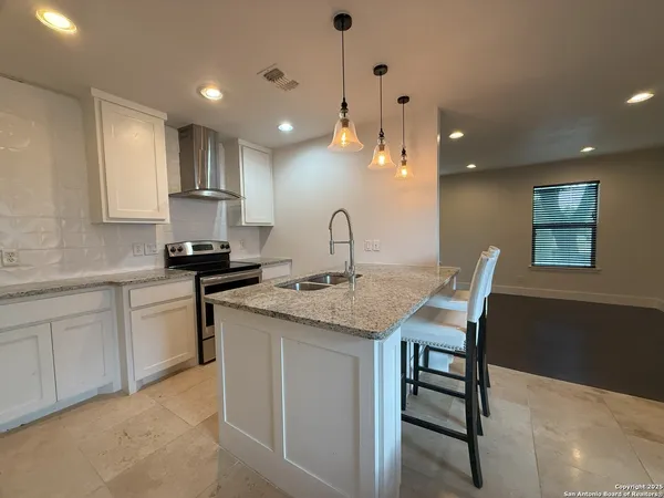 a kitchen with granite countertop a sink white cabinets and stainless steel appliances