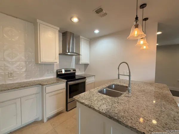 a kitchen with kitchen island granite countertop a sink stainless steel appliances and white cabinets
