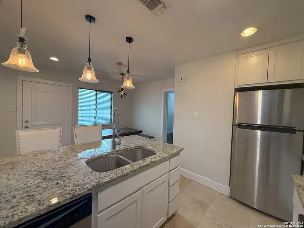 a kitchen with stainless steel appliances granite countertop a sink a refrigerator a counter and chairs