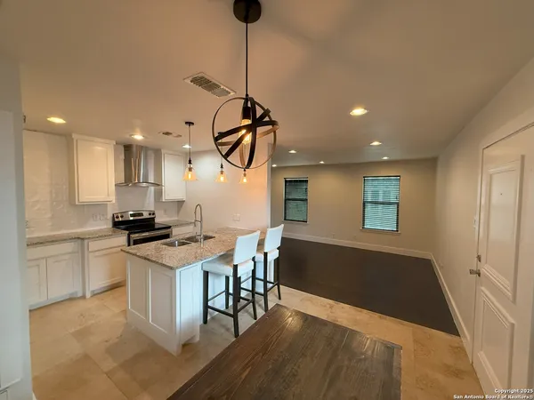 a kitchen with stainless steel appliances granite countertop a stove a sink a refrigerator and a dining table