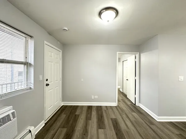 a view of an empty room with wooden floor and a window