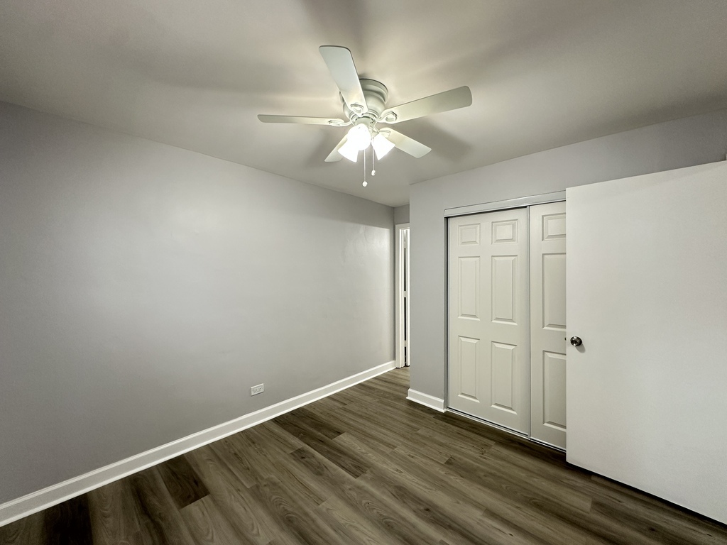 4616 North Beacon Street, Unit 2F Chicago, IL 60640 - Photo 16 of 21 an empty room with wooden floor fan and windows