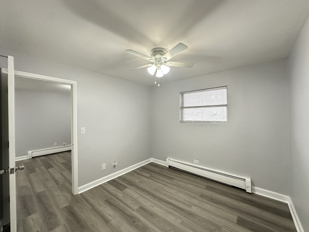 4616 North Beacon Street, Unit 2F Chicago, IL 60640 - Photo 18 of 21 an empty room with wooden floor fan and windows