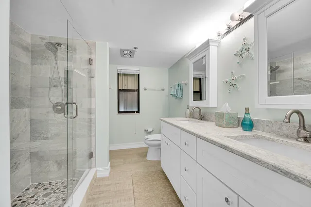 a bathroom with a double vanity sink toilet mirror and shower