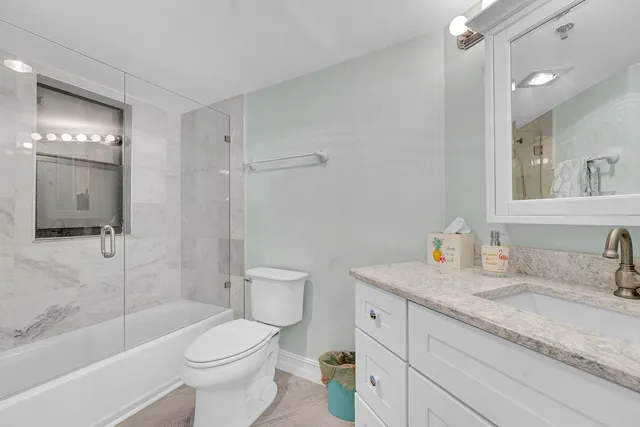 a bathroom with a granite countertop sink toilet and shower