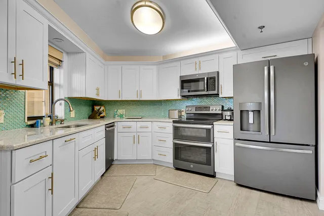 a kitchen with granite countertop white cabinets and stainless steel appliances