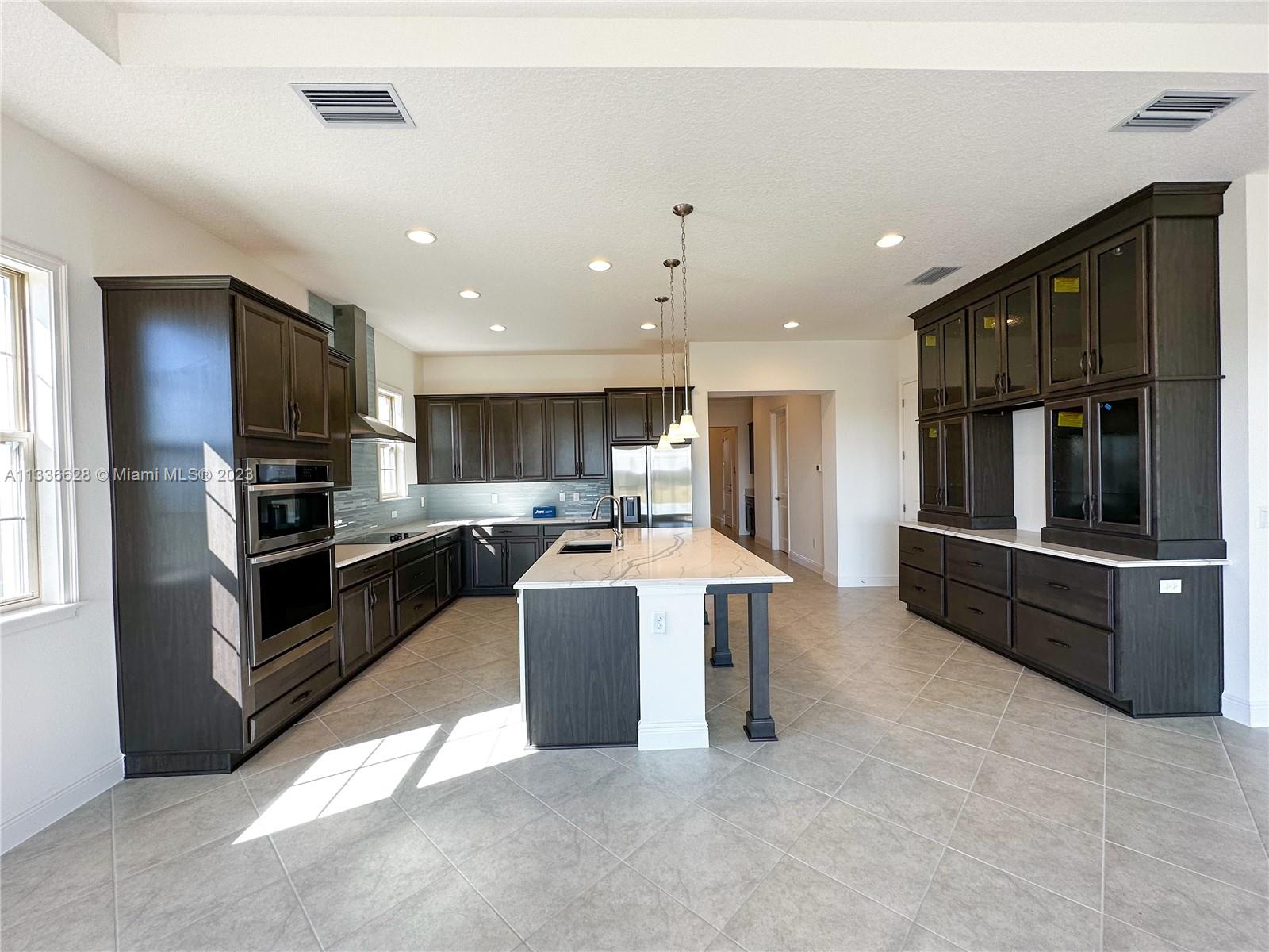 13646 Abberwick Drive Orlando, FL 32832 - Photo 11 of 50 a kitchen with kitchen island stainless steel appliances sink cabinets and stove top oven