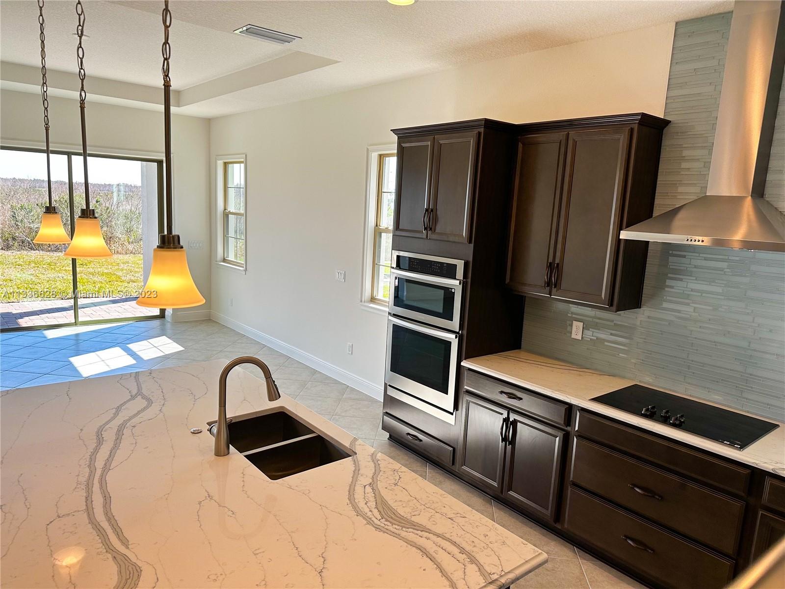 13646 Abberwick Drive Orlando, FL 32832 - Photo 3 of 50 a kitchen with stainless steel appliances kitchen island granite countertop a refrigerator a stove and a sink with wooden floor