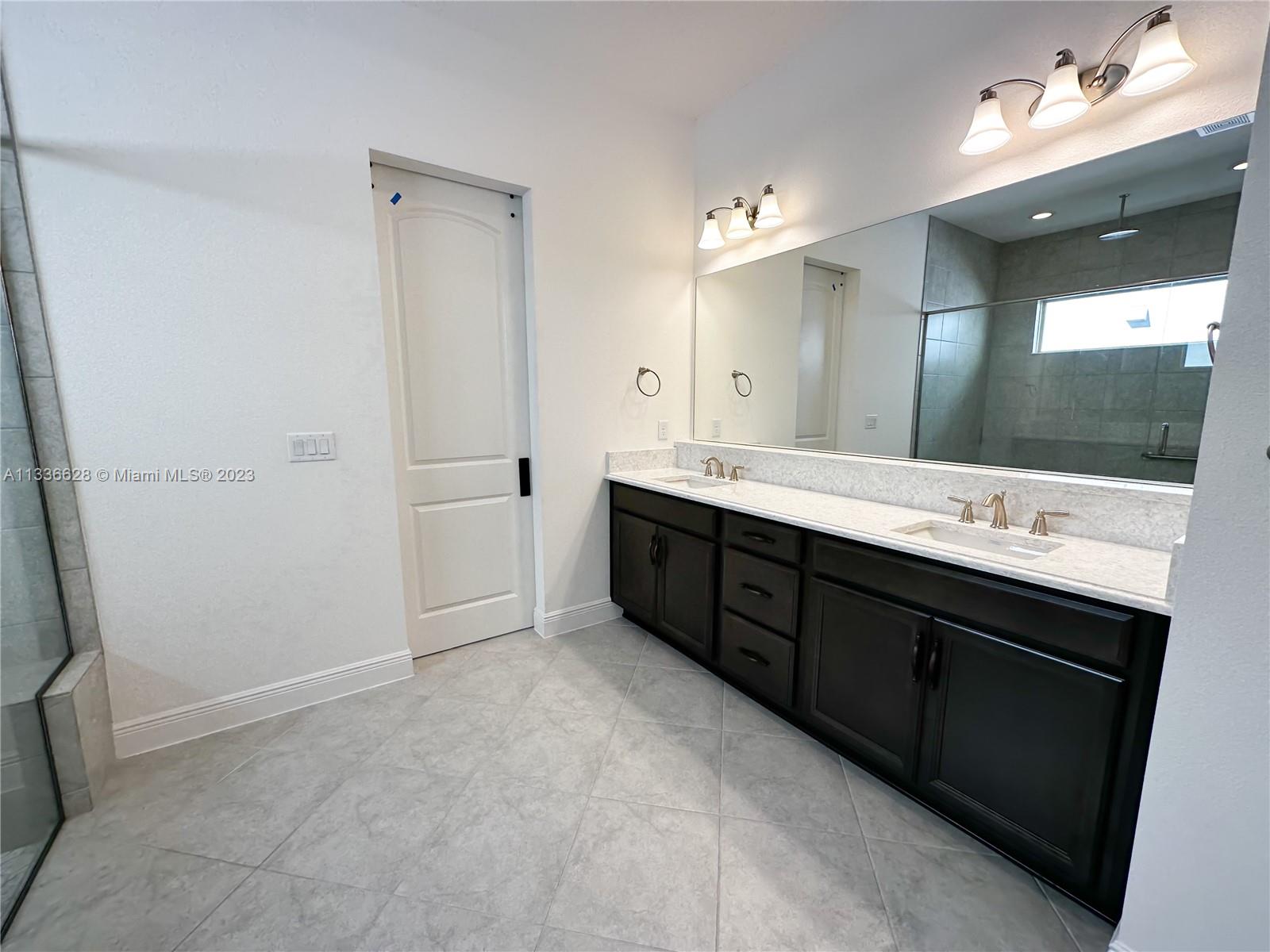 13646 Abberwick Drive Orlando, FL 32832 - Photo 7 of 50 a spacious bathroom with a double vanity sink a large mirror and a shower