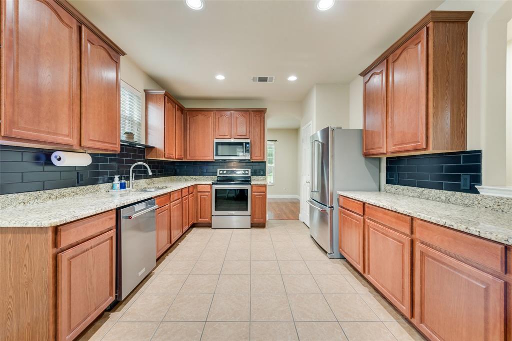 4521 Indian Paint Way Denton, TX 76208 - Photo 6 of 36 a large kitchen with stainless steel appliances granite countertop a stove a sink dishwasher a refrigerator and cabinets with wooden floor