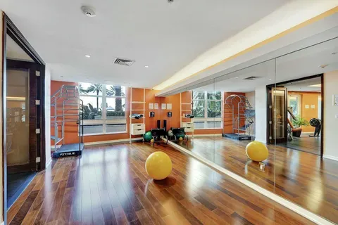 a gym room with lots of furniture and wooden floor