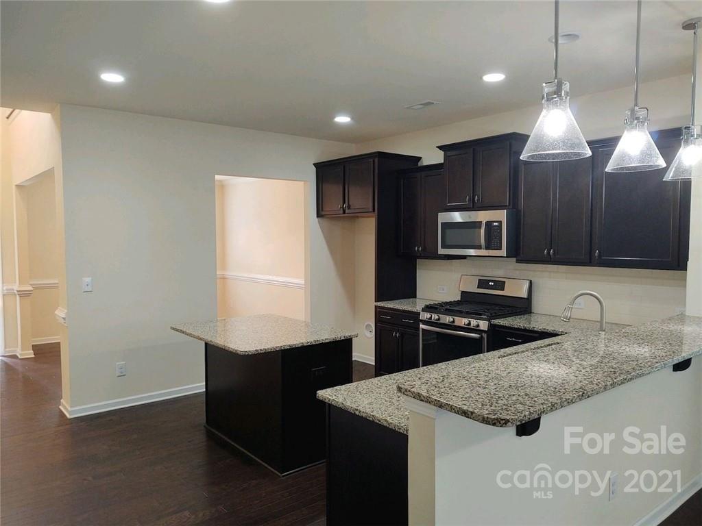 5077 Waterloo Drive Tega Cay, SC 29708 - Photo 4 of 15 a kitchen with kitchen island granite countertop stainless steel appliances a sink stove and refrigerator