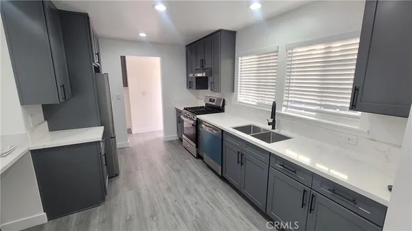 a large kitchen with stainless steel appliances a sink a refrigerator and a stove