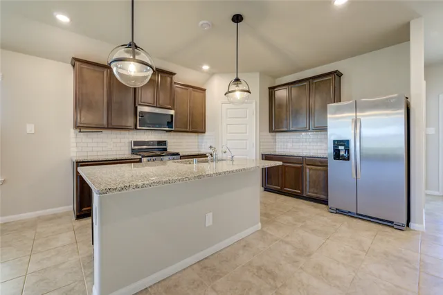 a kitchen with stainless steel appliances granite countertop a sink a stove and refrigerator