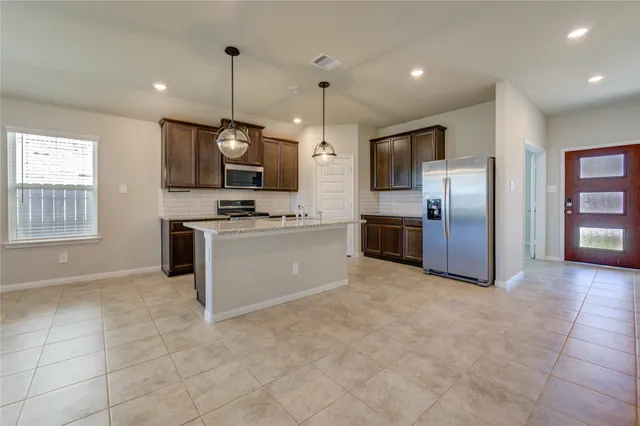 a kitchen with granite countertop stainless steel appliances a sink a counter space cabinets and wooden floor
