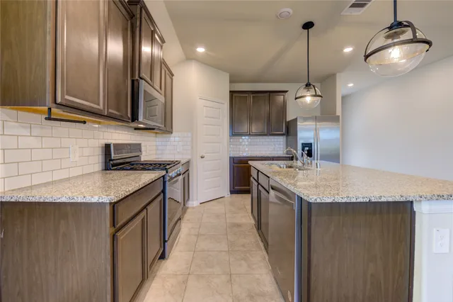 a kitchen with stainless steel appliances granite countertop a refrigerator a sink and a stove