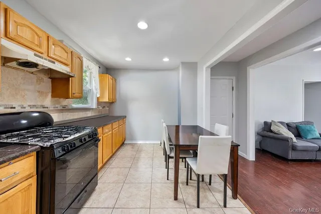 a kitchen with stainless steel appliances granite countertop a stove a sink a refrigerator white cabinets and wooden floor