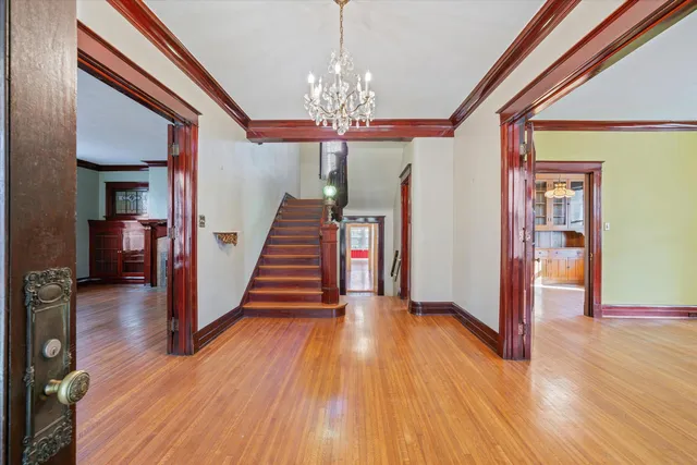 a view of a hallway with wooden floor staircase and a living room