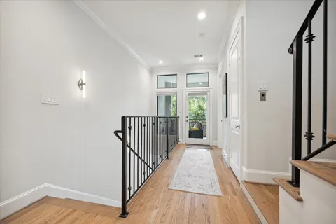 a view of a hallway with wooden floor and a bathroom