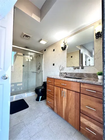 a spacious bathroom with a granite countertop sink mirror and shower