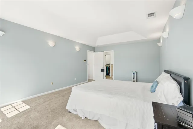 a spacious bedroom with a bed chandelier and a window