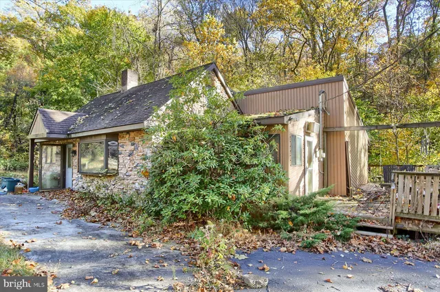 a view of a house with brick walls plants and large tree