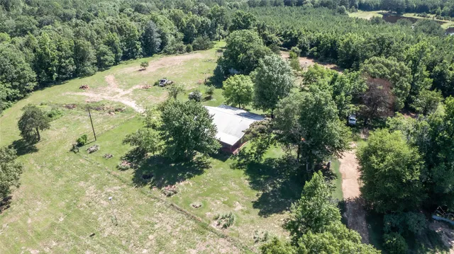 an aerial view of residential house with outdoor space and trees all around
