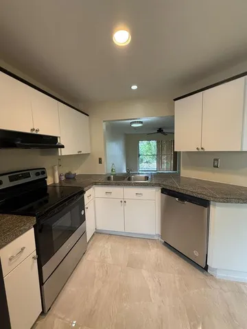 a kitchen with granite countertop a sink and white cabinets