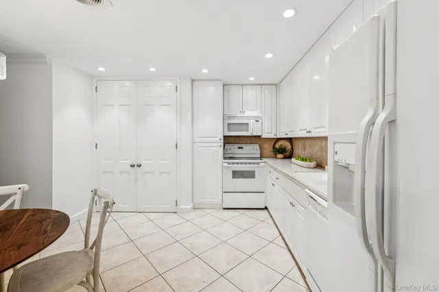 a kitchen with granite countertop white cabinets and white appliances