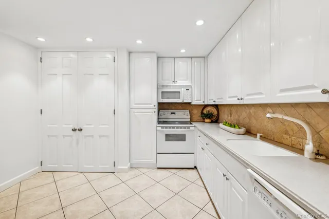 a kitchen with white cabinets and appliances
