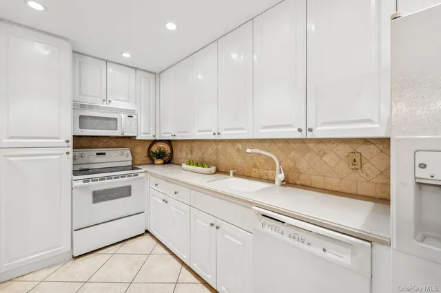 a kitchen with granite countertop white cabinets and white appliances