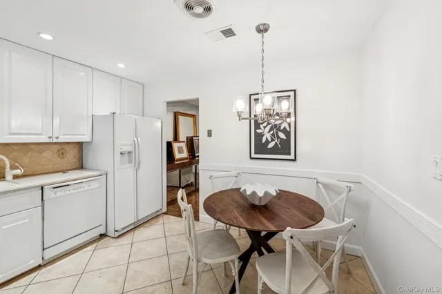 a kitchen with stainless steel appliances kitchen island granite countertop a dining table chairs and white cabinets
