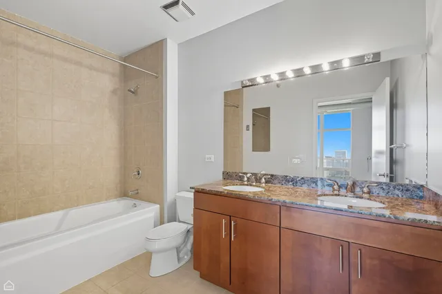 a bathroom with a granite countertop sink a toilet tub and shower