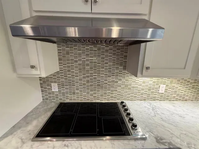 a bathroom with a granite countertop sink a stove and a shower