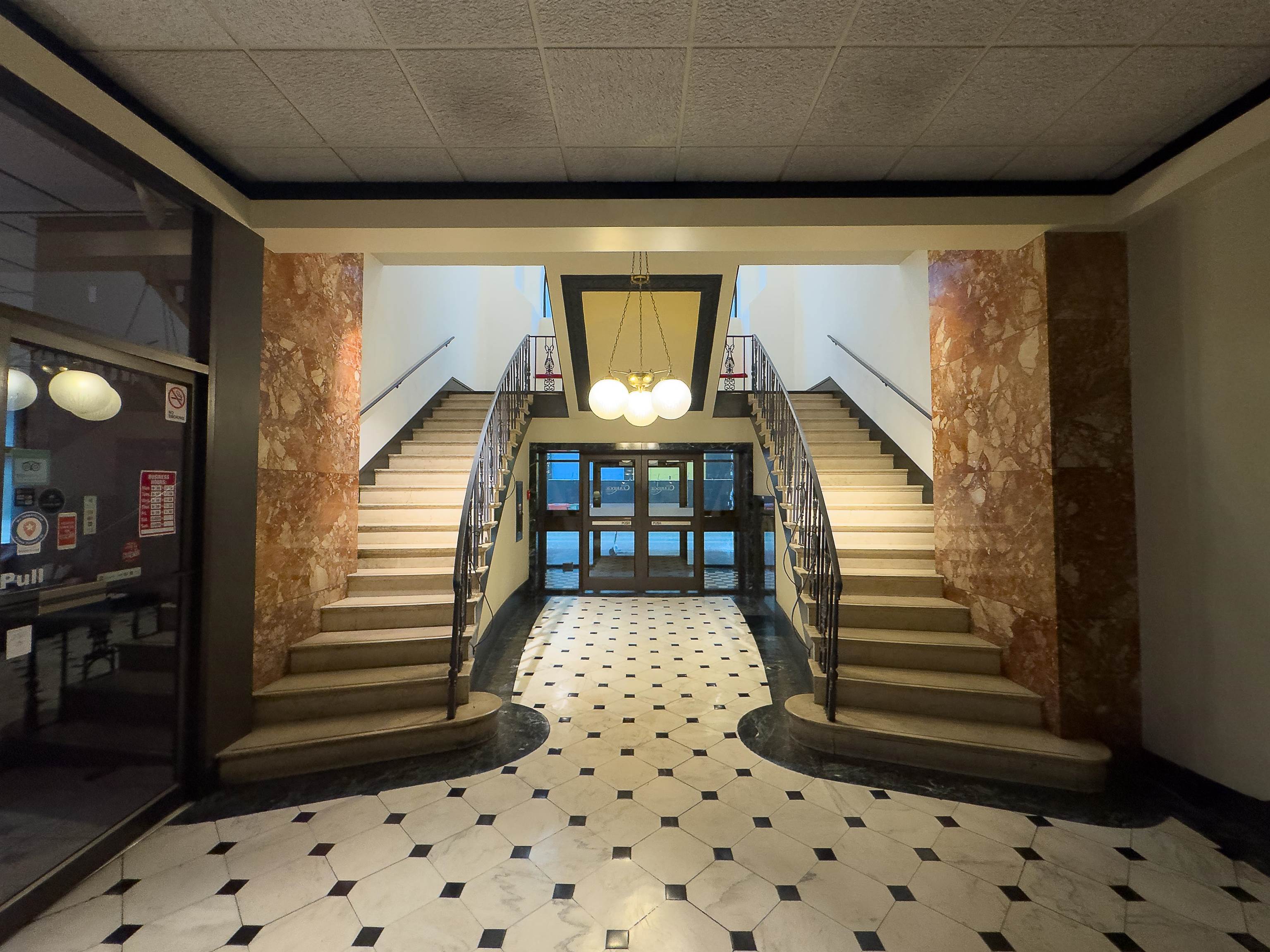 109 North Main Street, Unit 907 Memphis, TN 38103 - Photo 6 of 29 Symmetrical grand staircase with wrought iron railings, marble-clad columns, and a central chandelier