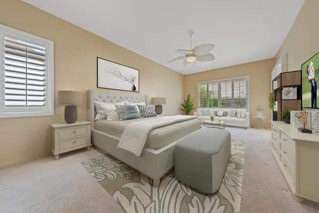 a bedroom with a large bed and a chandelier fan