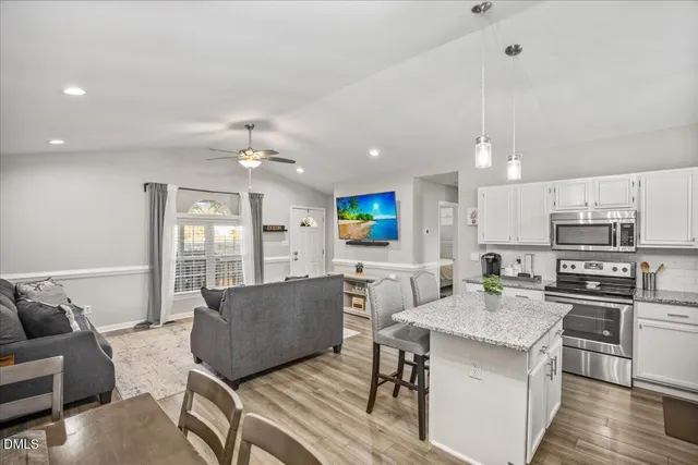 a living room with furniture kitchen view and a chandelier