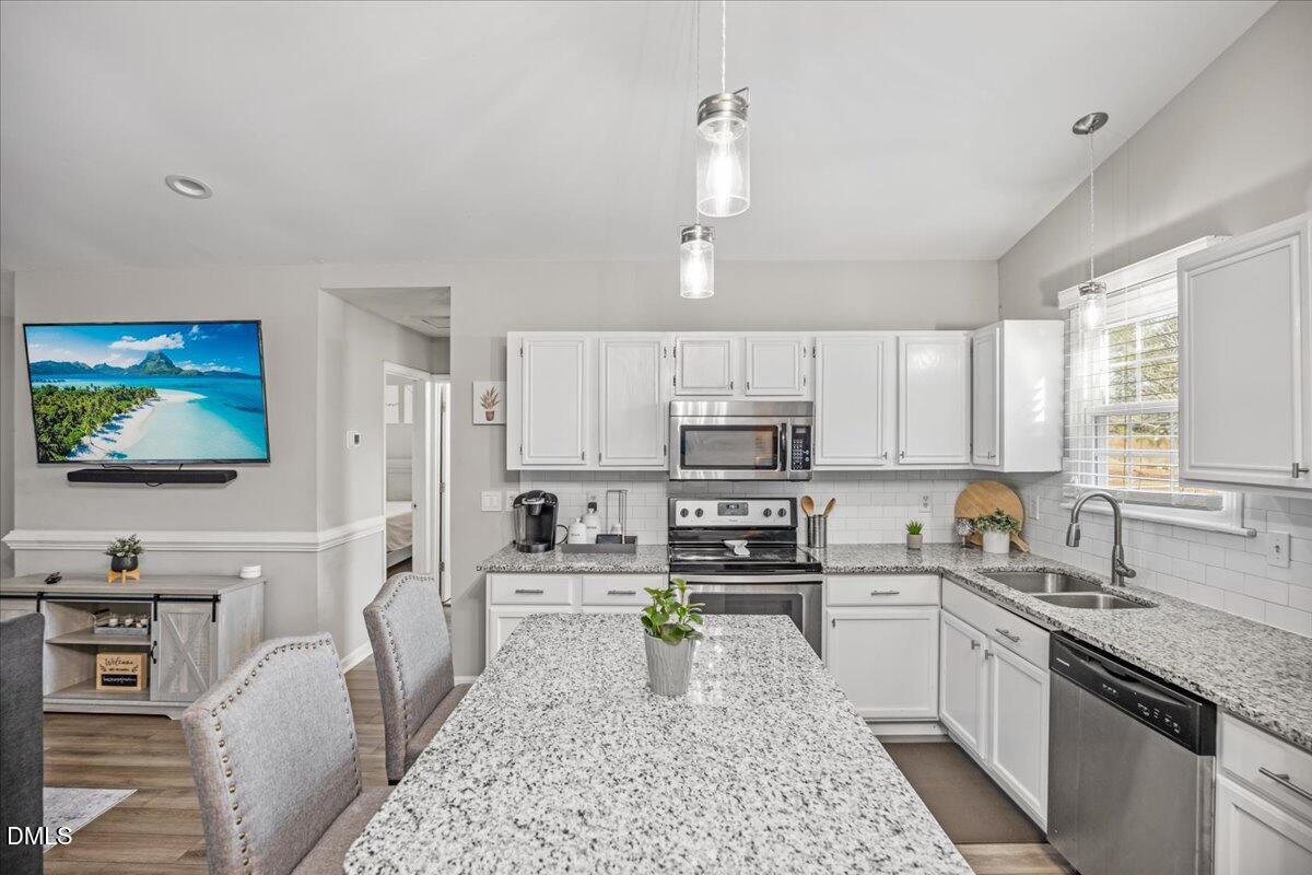 107 Claymont Road Louisburg, NC 27549 - Photo 4 of 30 a kitchen with stainless steel appliances kitchen island granite countertop a sink a stove top oven a counter space and cabinets